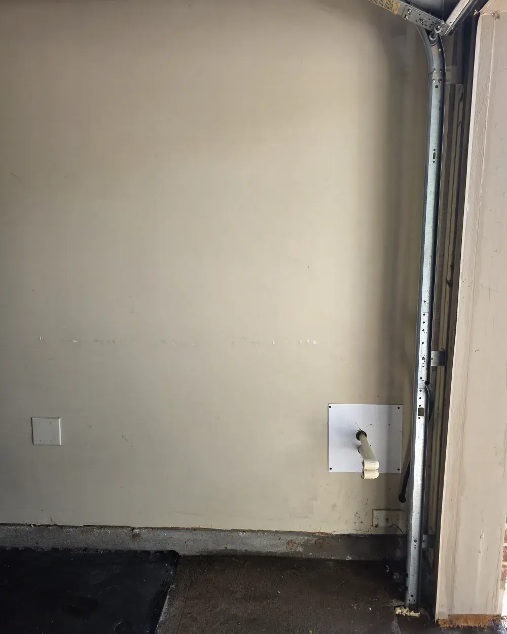 Bare garage wall before the job, with only the capped softener loop stubbed out through the wall plate.